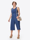 Mulher usa macacão feminino social em azul com detalhe de metal