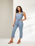 Mulher veste macacão jeans curto pantacourt e sandália de salto